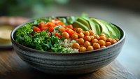 Healthy Buddha bowl with chickpeas, kale, cherry tomatoes and avocado slices in ceramic bowl on wooden table for nutritious meal planning.