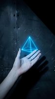 Glowing blue holographic pyramid floating above open palm against dark industrial metal background with scratches and rivets for futuristic technology concepts.