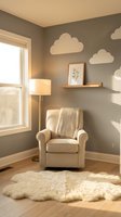 Cozy nursery corner with beige armchair, cloud wall decals, floating shelf and soft lighting creating peaceful atmosphere for baby care and relaxation.