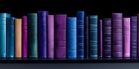 Row of vintage hardcover books in blue and purple shades standing on dark shelf against black background, creating minimalist library atmosphere.