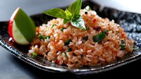 Delicious fried rice with fresh herbs and lime garnish served on dark plate. Asian cuisine dish with vegetables and aromatic basil leaves for restaurant menu.