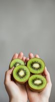 Fresh kiwi fruit slices held in hands against neutral background, showcasing vibrant green flesh and seeds for healthy eating and nutrition concepts.