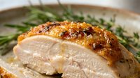 Roasted chicken breast with golden-brown skin served with fresh green beans on a ceramic plate, ready for fine dining or cookbook photography.
