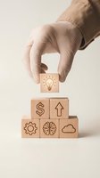 Hand placing wooden cube with lightbulb icon on pyramid of business symbol blocks representing innovation, growth, and strategic planning concepts.