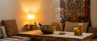 Cozy meditation room with singing bowl, incense, candles and traditional decor creating peaceful zen atmosphere for mindfulness practice and relaxation.
