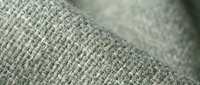 Close-up macro view of natural linen fabric texture showing detailed weave pattern and fiber structure in soft green tones for textile and material design.
