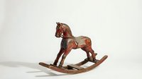 Antique wooden rocking horse with red paint and decorative details, vintage toy collectible on a light background.