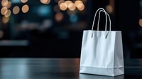 White paper shopping bag on dark surface with warm bokeh lights creating elegant retail and commercial atmosphere for marketing campaigns.