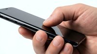 Close-up of male hand holding black smartphone with fingers positioned on sides, isolated on white background for tech product display and mobile device marketing.