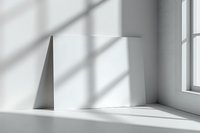 Minimalist white room interior with geometric shapes and dramatic window light casting diagonal shadows on wall and floor. Clean modern aesthetic space.