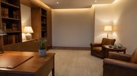 Modern home office interior with wooden desk, leather armchair, built-in bookshelves and warm ambient lighting for professional workspace design.