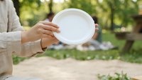 Woman holding empty white plate outdoors in garden setting, suitable for food styling, nutrition concepts, healthy eating campaigns, and culinary content.