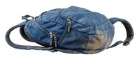 Worn blue denim backpack with dual shoulder straps and front zippered pockets, showing faded fabric and weathered texture, suitable for travel, casual wear, and lifestyle photography.