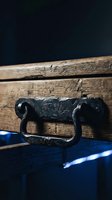 Vintage wooden chest with ornate black metal handle and lock mechanism on blue surface against dark background for antique decor projects.