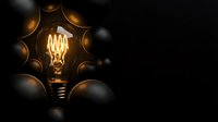 Glowing vintage filament light bulb surrounded by dark spheres on black background, representing innovation, ideas, and creative thinking concepts.