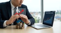 Professional businessman analyzing financial growth with percentage symbol, laptop showing investment charts, and stacked coins representing wealth building strategies.