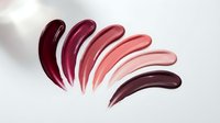 Colorful lipstick swatches in burgundy, pink and nude tones arranged in curved strokes on white background for beauty and cosmetics branding.