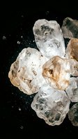 Crushed ice cubes and rock salt crystals scattered on black background with dynamic motion and splashing particles, suitable for beverage, food, and cooling product advertising.
