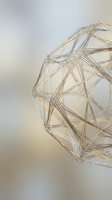 Golden wireframe sphere with geometric polygonal structure and interconnected nodes on soft gradient background for modern design projects.