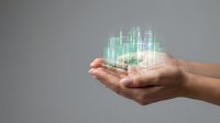 Young adult male hands holding glowing holographic cityscape with skyscrapers, representing smart city technology, urban development, and digital innovation for business and real estate concepts.