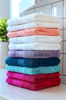 Stack of colorful cotton towels neatly folded in bathroom setting with natural light for home decor and textile concepts.