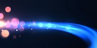 Glowing blue light trail with pink and orange bokeh effects on dark background creates magical energy flow effect for abstract design projects.