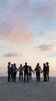 Group of diverse people holding hands in silhouette against pastel sunset sky on beach, symbolizing unity, teamwork and togetherness in nature.