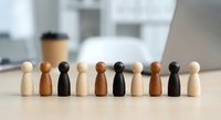 Diverse wooden figurines representing multicultural team unity and inclusion in modern office workspace for business concepts.