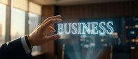 Businessman hand touching glowing BUSINESS text hologram in modern office with city lights background for corporate strategy and growth concepts.