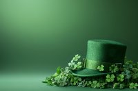 Green leprechaun hat decorated with shamrock clover leaves on emerald background with copy space. St Patrick's Day festive holiday celebration concept.