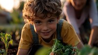 Young boy in yellow t-shirt and overalls smiling while gardening outdoors, holding fresh green vegetables during sunset, expressing joy and connection with nature.