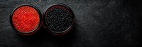 Red and black caviar in glass bowls on dark stone background, luxury seafood delicacy captured in minimalist style with copy space for menu design.