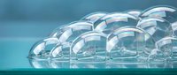 Abstract transparent soap bubbles floating on turquoise blue surface creating dreamy ethereal atmosphere for spa wellness and relaxation concepts.