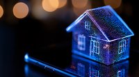 Glowing miniature house model illuminated in neon blue light with smartphone nearby on dark surface against blurred bokeh background creates magical atmosphere.