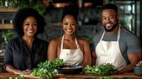 Three happy African American friends cooking together in modern kitchen wearing aprons, preparing fresh green vegetables for healthy meal preparation.