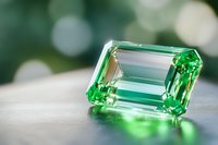 Emerald cut green gemstone on blurred bokeh background showcases brilliant facets and clarity, suitable for jewelry advertising and luxury marketing materials.