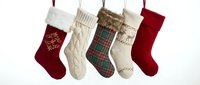 Five festive Christmas stockings hanging on rope display traditional holiday colors and patterns including cable knit, plaid, and embroidered designs for seasonal decor.