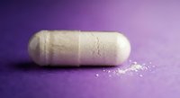 White capsule pill on purple gradient background with powder spilling out for pharmaceutical and healthcare concepts.