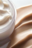 Smooth creamy texture with soft beige and white swirls creating elegant waves and curves, macro photography showing luxurious cosmetic moisturizer surface detail.