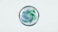 Glass sphere containing swirling blue and green liquid creating dynamic spiral pattern on white background isolated for design projects.