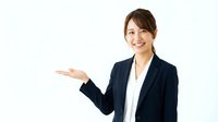 Professional Asian businesswoman in navy suit presenting with open palm gesture on white background for corporate marketing materials.