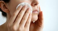 Young woman gently cleansing face with cotton pad in daily skincare routine for healthy glowing skin and facial care regimen.