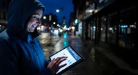Young woman using tablet computer on city street at night with urban lights and bokeh background for digital technology and connectivity concepts.