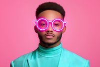 Young African American man wearing turquoise turtleneck sweater and bright neon pink glasses against pink background, modern fashion portrait with vibrant colors.