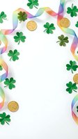 St Patrick's Day festive frame with green shamrocks, gold coins and rainbow ribbon on white background for Irish holiday celebration and party decorations.