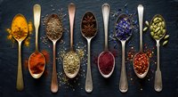 Colorful spices and herbs arranged in wooden spoons on dark slate background. Culinary ingredients for cooking and seasoning food preparation.