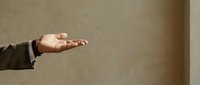Male hand in open palm gesture against neutral beige wall background, conveying offering, acceptance, or presentation concept for business and communication designs.