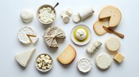 Assortment of various cheese types including soft brie, hard cheddar, blue cheese and fresh mozzarella arranged on white background for culinary and gourmet food concepts.