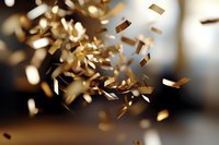 Golden confetti pieces falling and floating in air with warm bokeh lights creating festive celebration atmosphere for parties and special events.