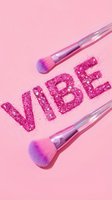 Makeup brushes with pink glitter spelling vibe on pastel background. Cosmetics and beauty products for makeup application, eyeshadow, and artistic design projects.
